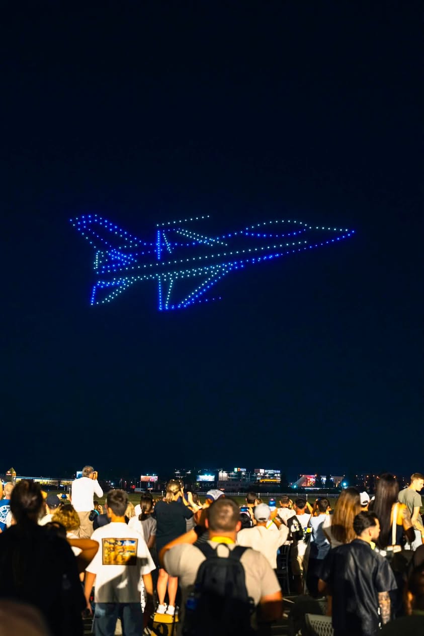 A fighter aircraft outlined in drones against the night sky above the BIAS 2026 crowd