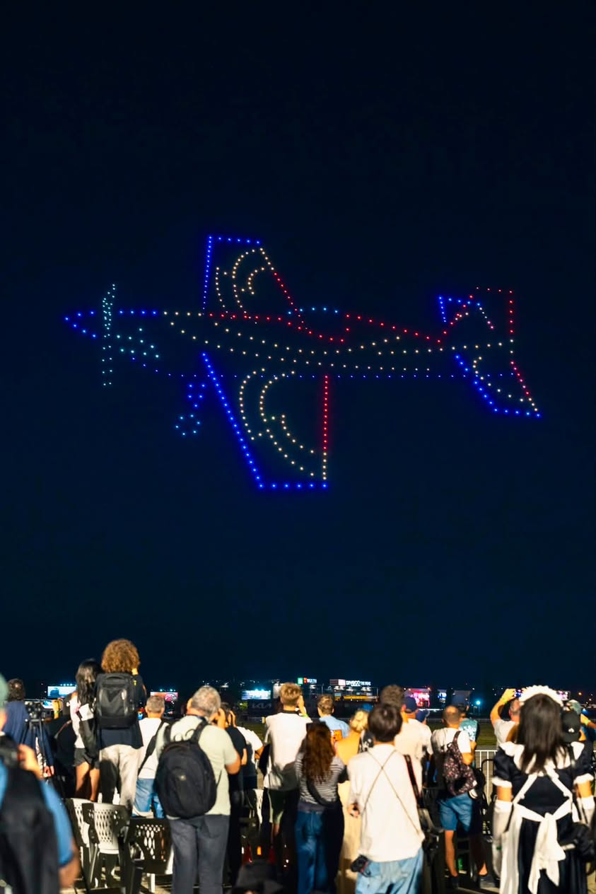 An aerobatic aircraft outlined in drones against the night sky at BIAS 2026